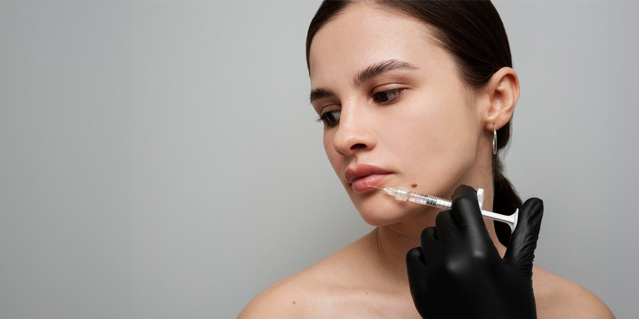 A woman receiving an injection on her bottom lip. 