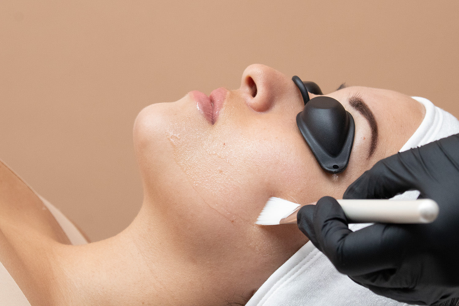 A woman receiving a cosmetic treatment on her face.