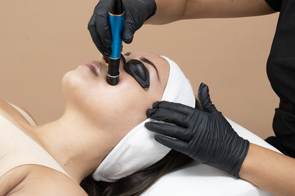 A woman receiving a cosmetic treatment on her face.