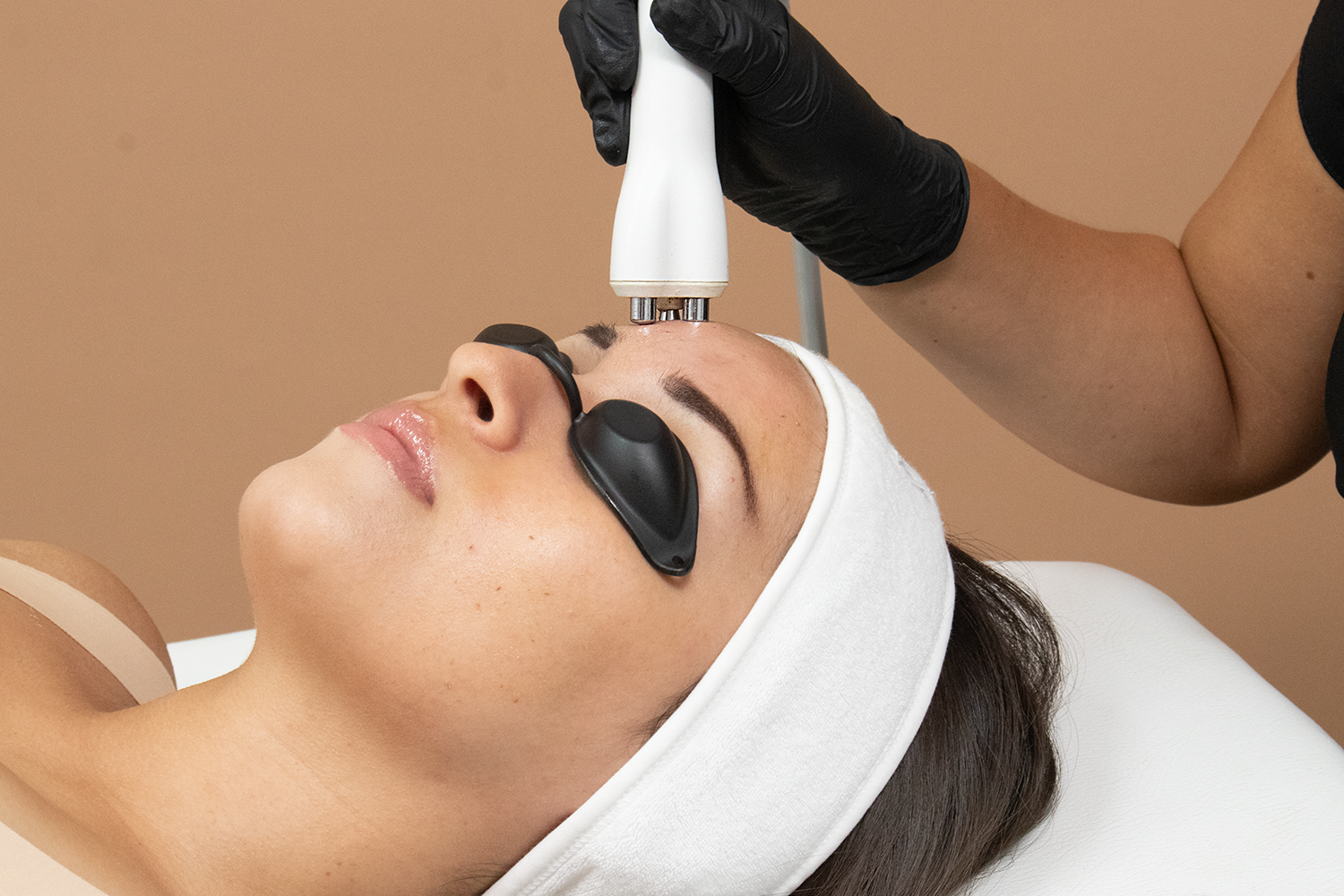 A woman receiving a cosmetic treatment on her face.