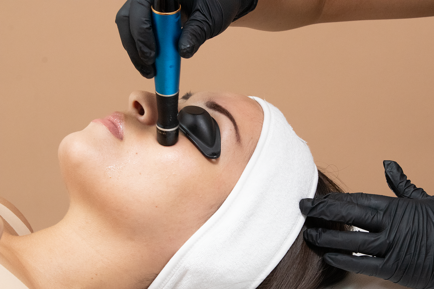 A woman receiving a cosmetic treatment on her face.